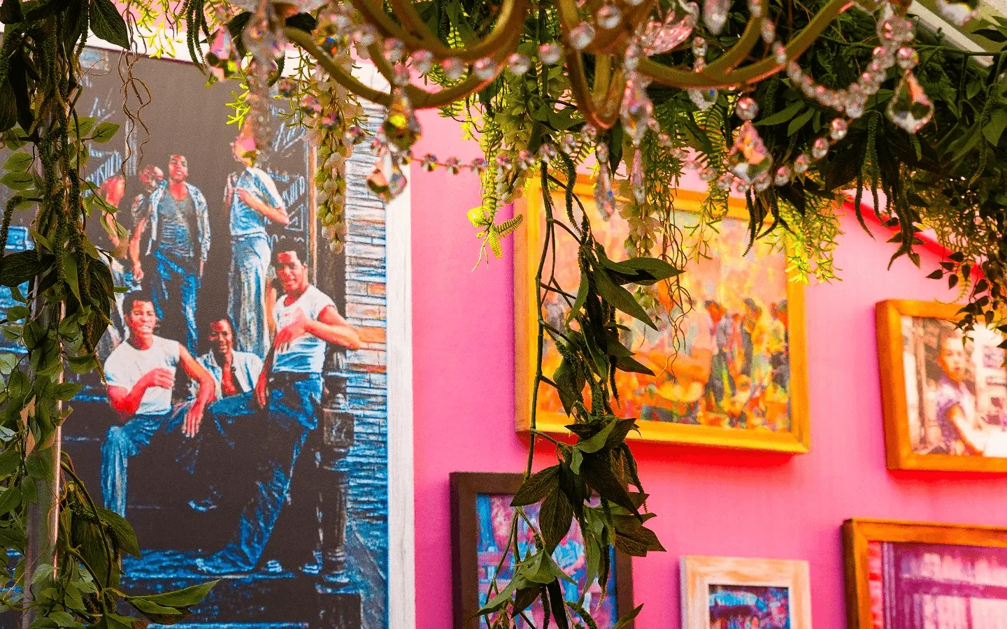 The pink wall of framed photographs under hanging greenery inside Uncle Rocco, Hoboken