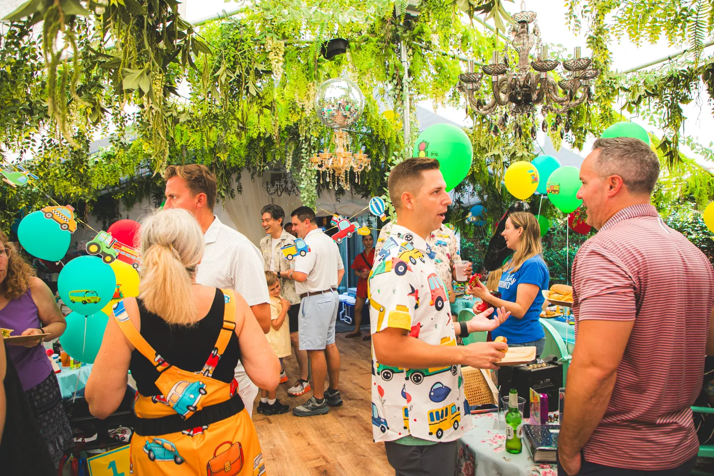 Guests at a private party in the Uncle Rocco backyard, under hanging greenery and chandeliers