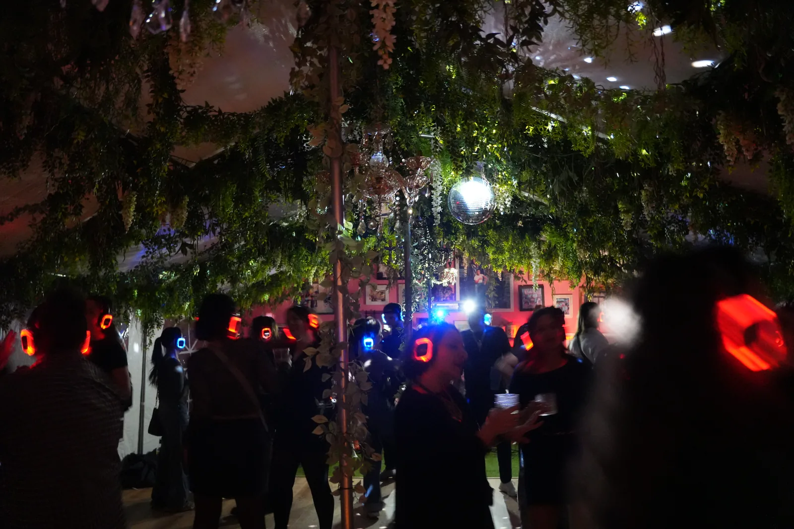 Guests wearing glowing headphones at a silent disco in the Uncle Rocco backyard