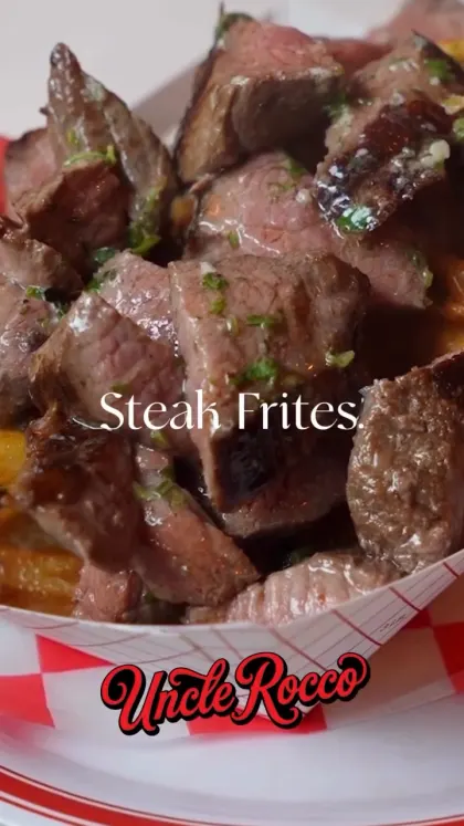 Steak Frites at Uncle Rocco, pieces of hanger steak with chopped herbs piled over fries in a red and white paper boat, with the restaurant logo on the frame