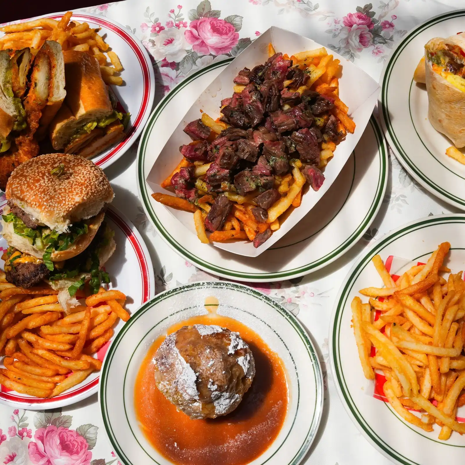 Overhead spread of burgers, sandwiches, steak frites and sides at Uncle Rocco